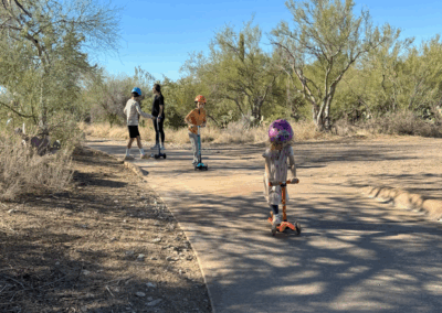 Image shows a family enjoying the trail with scooters and skateboards.