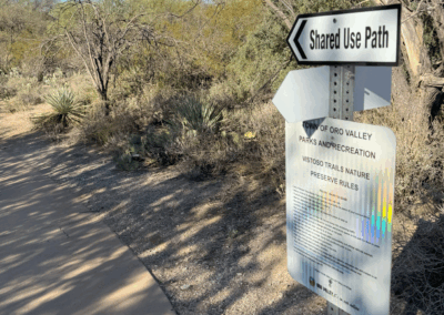Image shows a sign directing hikers to intersecting paths along a Shared-use trail.