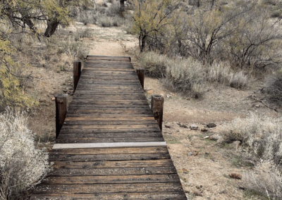 Image shows a wooden bridge straddles a dry wash along the trail.