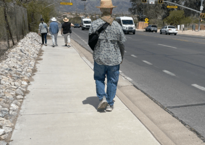 Image shows a group of hikers on a paved sidewalk along Craycroft Road, leading to Fort Lowell Road.