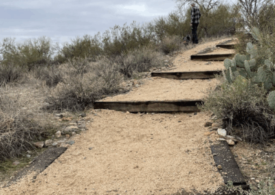 Image shows stair steps built from railroad ties up a desert incline which protects the trail against erosion.