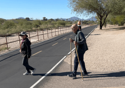 Image shows hikers transitioning between the packed-earth trail and the paved bike path.