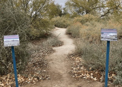 The image shows informative signs at one of the trail forks.
