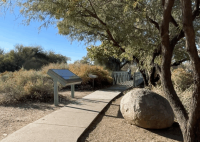 Image shows a cement path that offers a 0.25-mile tour through the wetlands with ramadas and interpretive signs.
