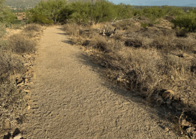 Image shows a flat, wide, and well-packed trail with mountains in the distance.