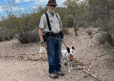 Image of a man and his leashed dog standing in front of cacti.