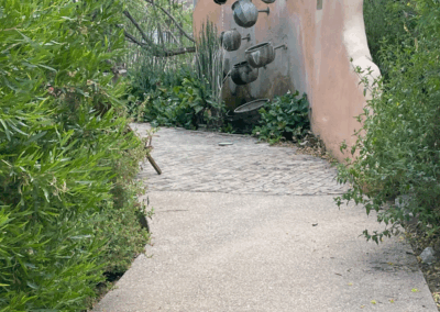 Image of a paved trail through lush fauna and an interesting waterfall sculpture.