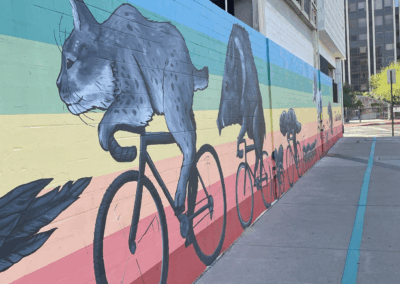 Image of a mural depicting several animals riding bicycles in a rainbow wall.