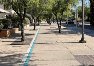 Image of a tree-lined sidewalk painted with a turquoise line which marks the turquoise trail path.