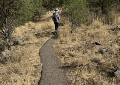 Image of a hiker walking along a narrow, paved portion of the Accessible Trail.