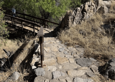 Image of a rock-paved part of the Accessible Trail leading to a bridge over the creek.